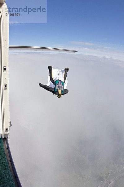 Mittlerer Erwachsener Mann  der im Wingsuit über Wolken fliegt.