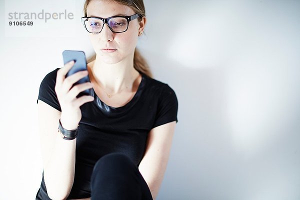 Junge Frau mit Brille über Smartphone