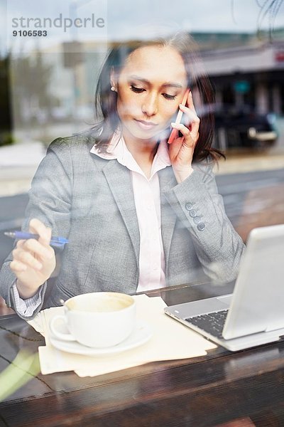 Junge Geschäftsfrau übernimmt Smartphone im Café