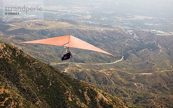 Mann fliegt Hängegleiter über das Tal