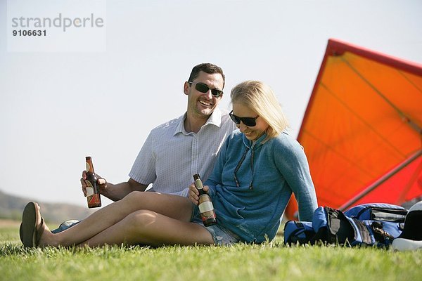 Paar beim Bier entspannen  Drachenflieger im Hintergrund