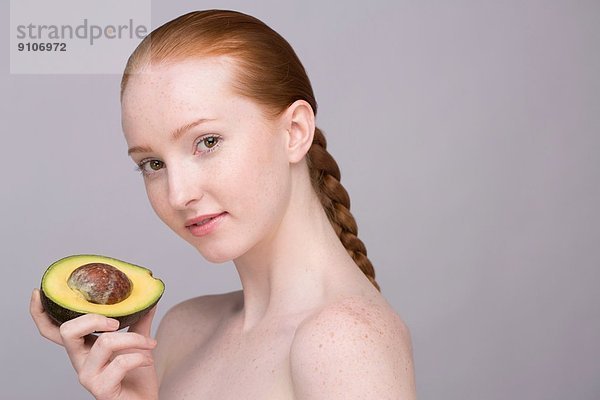 Porträt einer jungen Frau  die Avocado hält