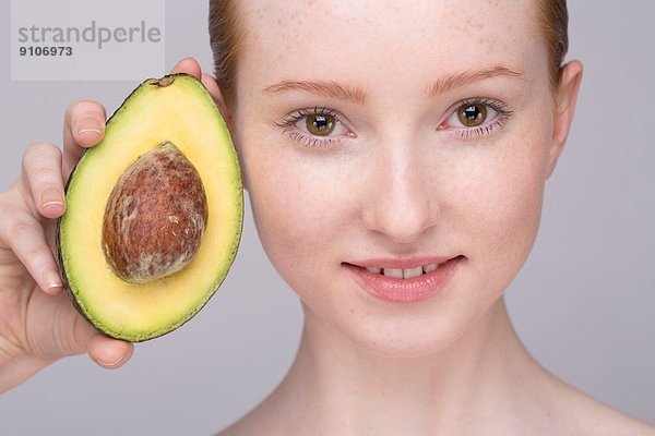 Porträt einer jungen Frau  die Avocado hält