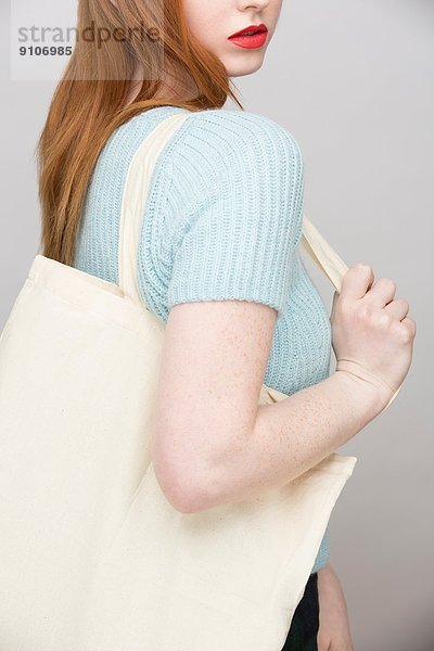 Abgeschnittenes Bild einer jungen Frau mit Einkaufstasche