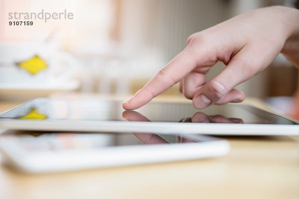Nahaufnahme der Hand der jungen Frau mittels Touchscreen auf digitalem Tablett