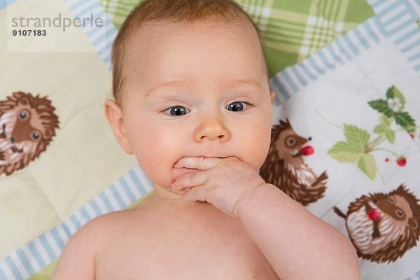 7 Monate altes Mädchen im Kinderbett mit Fingern im Mund