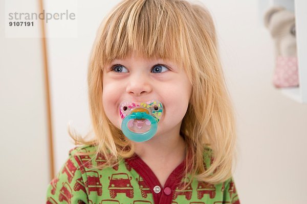 Porträt eines glücklichen 2-jährigen Mädchens mit Schnuller
