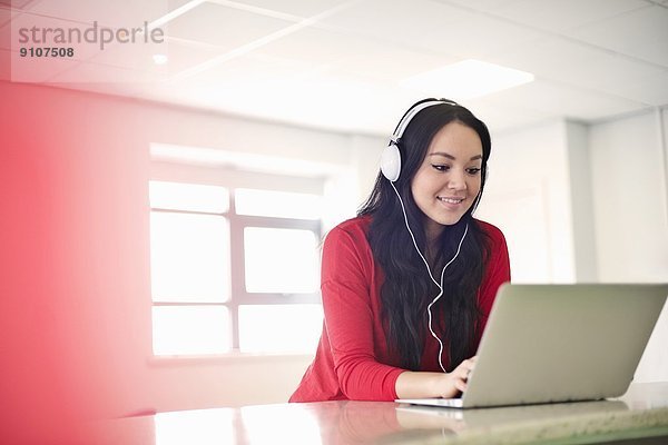 Junge Frau mit Kopfhörer am Laptop