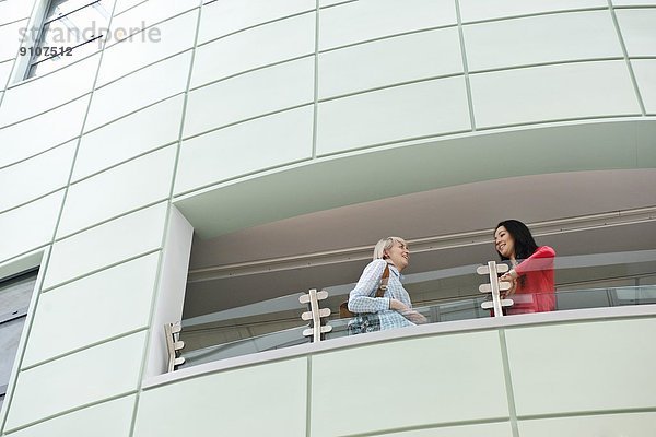 Zwei junge Frauen sprechen auf dem Balkon  niedriger Winkel