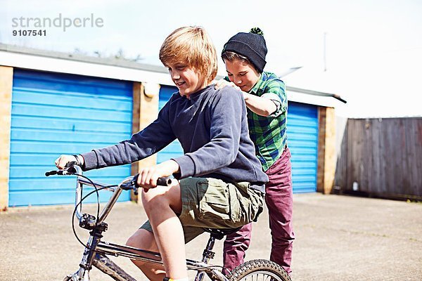 Junge  der einen Freund auf dem Fahrrad mitnimmt.