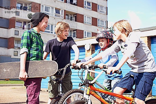 Gruppe von Jungen im Gespräch mit Fahrrädern und Skateboard