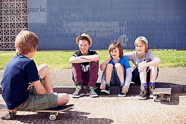 Jungen sitzen auf dem Bürgersteig mit Skateboards