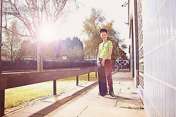 Porträt eines Jungen auf dem Bürgersteig mit Skateboard