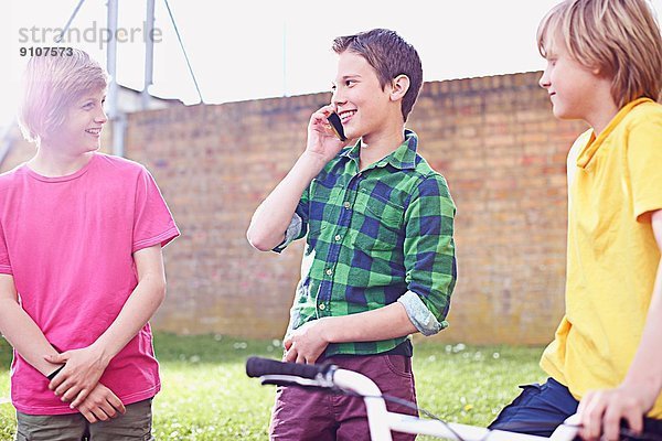 Junge benutzt Handy mit zwei Freunden