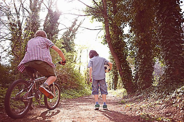 Junge auf Fahrrad mit Freund auf Waldweg