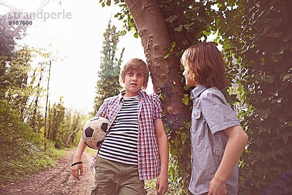 Jungen reden am Baum mit Fußball