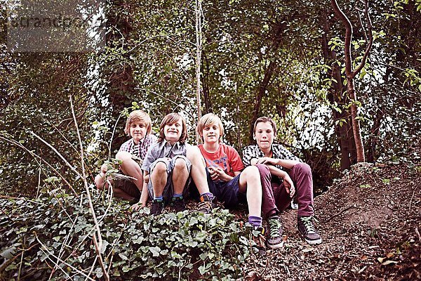 Porträt von vier Jungen im Wald sitzend