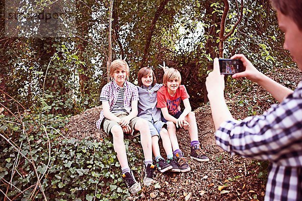 Junge fotografiert Freunde mit Telefon im Wald