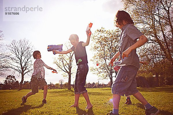 Jungen spielen mit Schaumstoffpfeilern im Park
