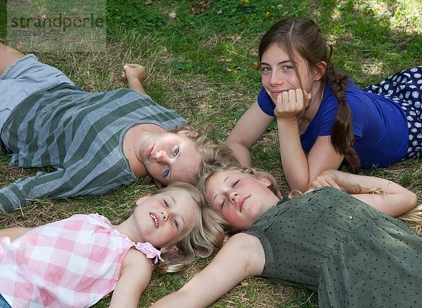 Vier Mädchen auf Gras liegend