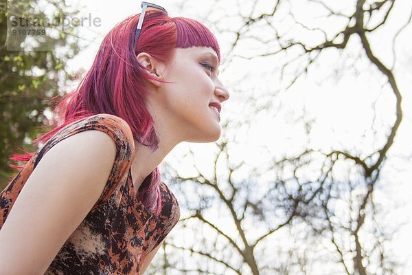 Porträt einer lächelnden jungen Frau mit rosa Haaren