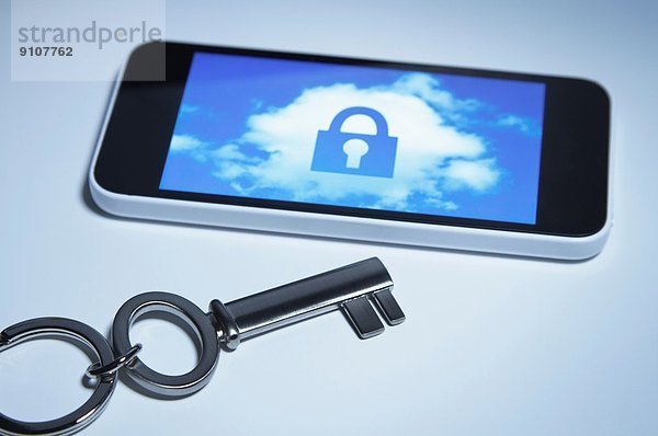 Sicheres Smartphone. Ein Schlüssel neben dem Smartphone mit einem Schloss über einer Wolke auf dem Bildschirm.