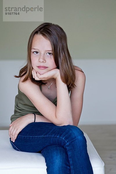 Porträt eines mürrischen zwölfjährigen Mädchens mit Hand am Kinn
