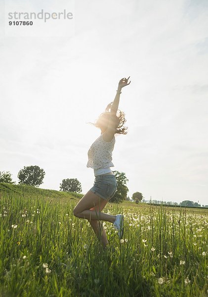 Junge Frau beim Springen im Feld