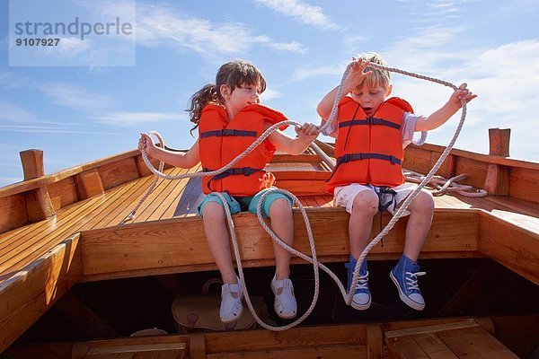 Zwei Kinder sitzen im Boot und halten ein Seil