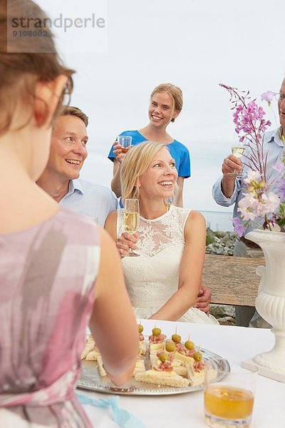 Mittleres erwachsenes Paar  das einen Toast mit einer Gruppe von Freunden bei der Hochzeitsfeier ausspricht.