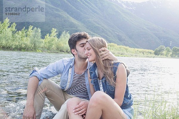 Junger Mann küsst Freundin am Toce Flussufer  Piemonte  Italien