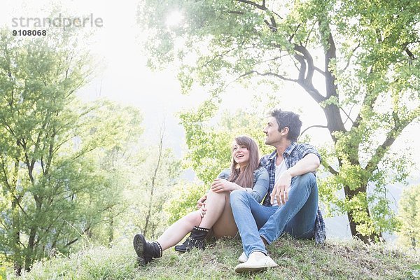 Junges Paar auf Rasen sitzend  Piemont  Italien