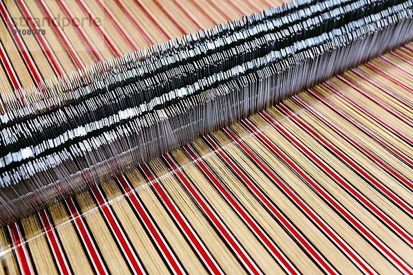 Nahaufnahme von gestreiften Textilien auf der Webmaschine in der Wollmanufaktur