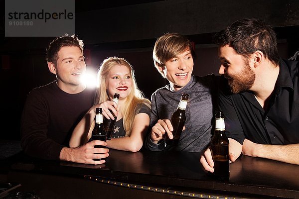 Vier Freunde trinken Flaschenbier im Nachtclub