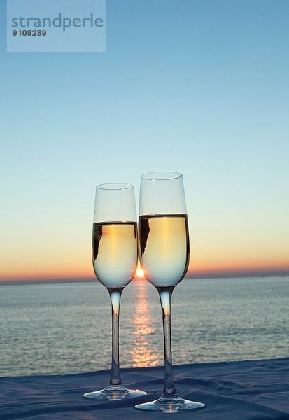 Zwei Champagnerflöten gegen Sonnenuntergang