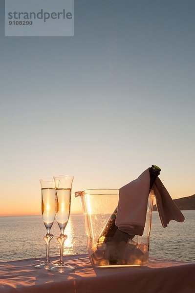 Champagnerflöte und Eimer gegen Sonnenuntergang