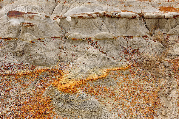Erosion patterns in bentonite bluffs  with orange capstone layer