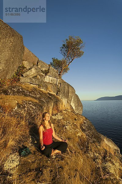 junge Frau junge Frauen Meditation vorwärts Felsenküste