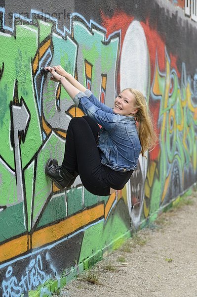 Junge Frau an einer Graffitiwand  Nürnberg  Bayern  Deutschland  Europa