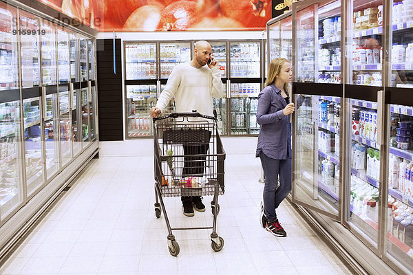 Die ganze Länge von Vater und Tochter beim Einkaufen im Supermarkt