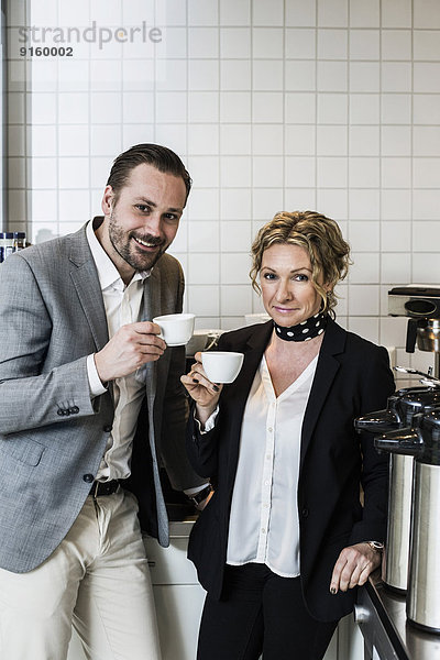 Porträt von lächelnden Geschäftsleuten beim Kaffee in der Küche