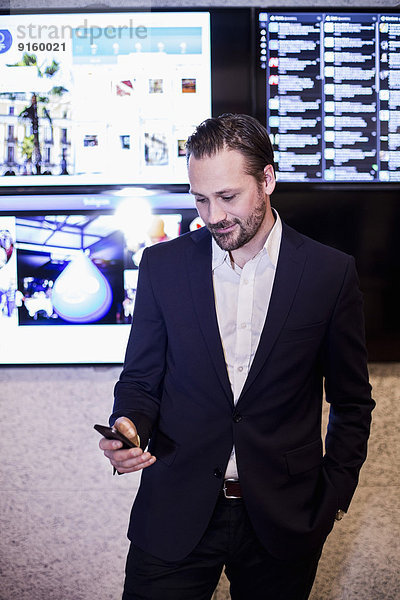 Mittlerer Erwachsener Geschäftsmann mit Handy im Büro