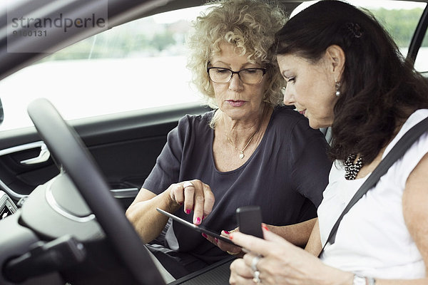 Senioren-Freundinnen mit digitalem Tablett im Auto