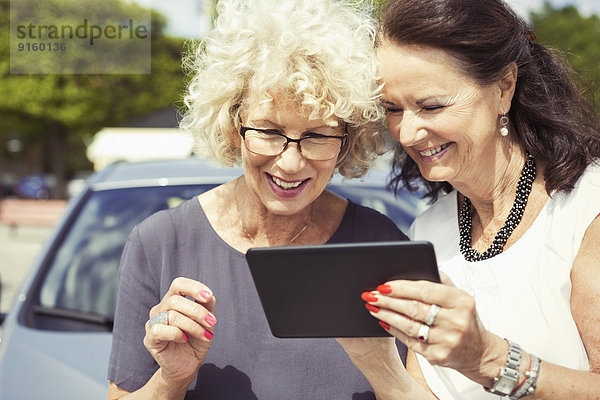 Glückliche Senioren-Frauen mit Digital-Tablett im Freien