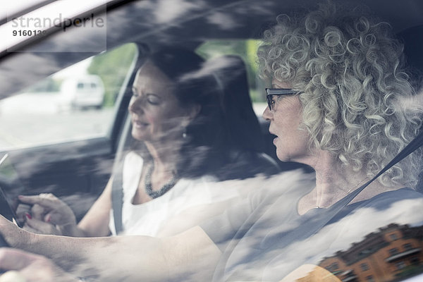 Seniorinnen diskutieren über digitales Tablett im Auto