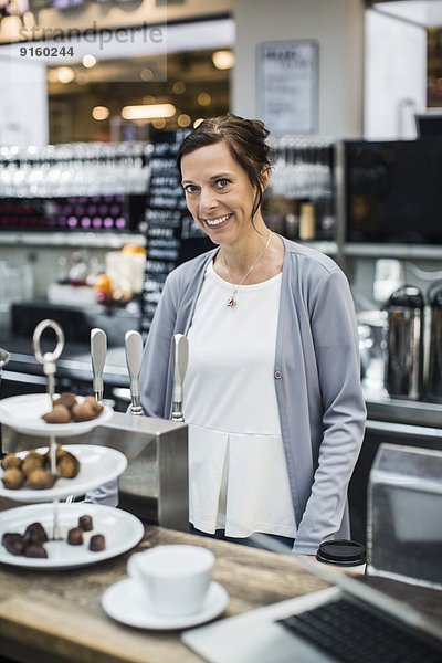 Porträt der lächelnden reifen Besitzerin am Cafe Tresen