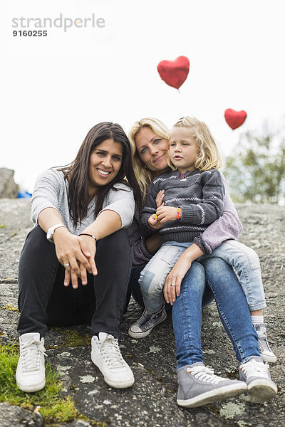 Porträt einer glücklichen homosexuellen Familie  die sich auf dem Felsen ausruht