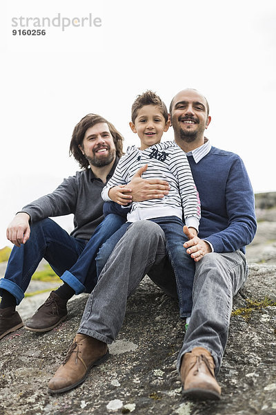 Porträt einer glücklichen homosexuellen Familie  die sich auf dem Felsen ausruht