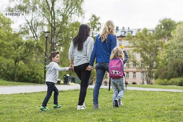 Rückansicht der weiblichen homosexuellen Familie beim Spaziergang im Park