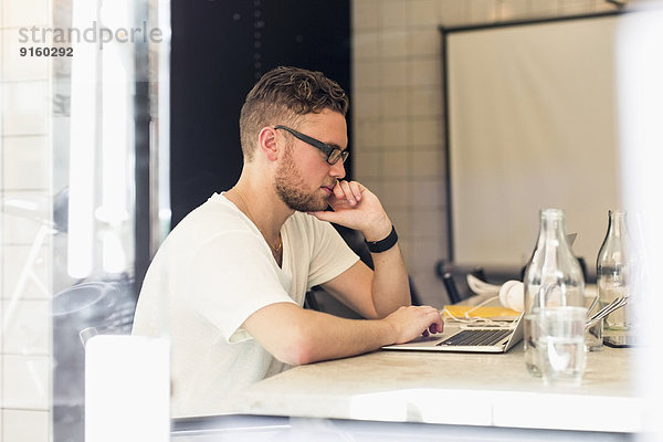 Seitenansicht des jungen Geschäftsmannes mit Laptop im Kreativbüro